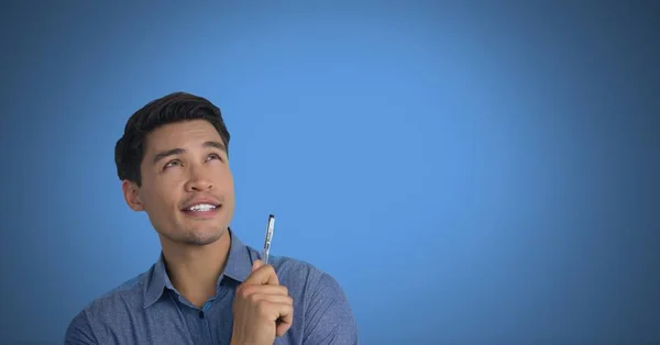 Uomo d'affari che tiene penna con sfondo blu — Foto Stock