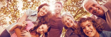 güneşli bir günde parkta gülümseyen aile