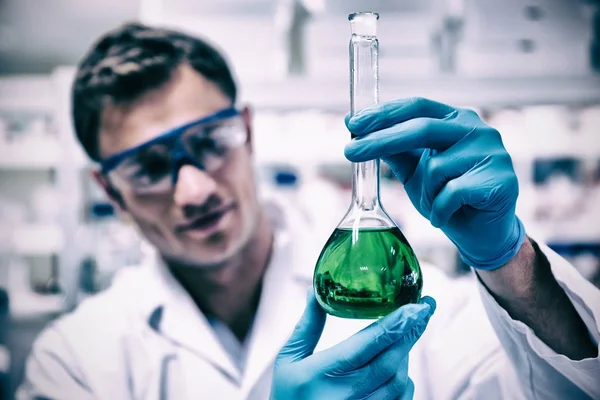 Chemist holding up beaker of chemical — стоковое фото