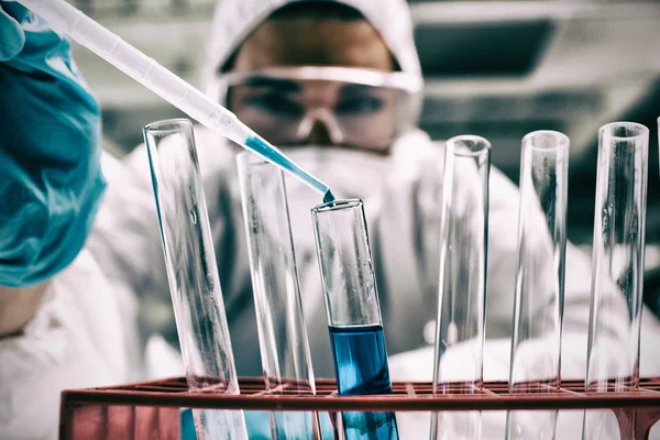 Student lässt blaue Flüssigkeit im Reagenzglas fallen — Stockfoto