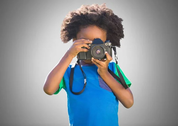 Boy against grey background with camera — Stock Photo, Image