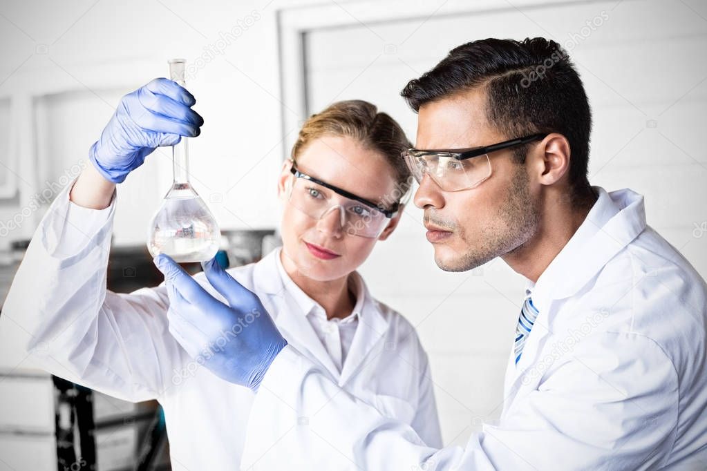 Concentrated scientists looking at beaker 