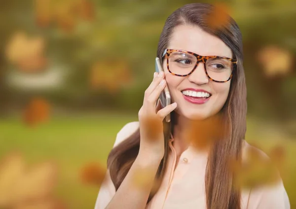 Kvinna på telefon i skogen med blad — Stockfoto