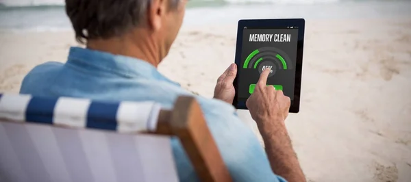 Человек с помощью цифрового планшета на пляже — стоковое фото