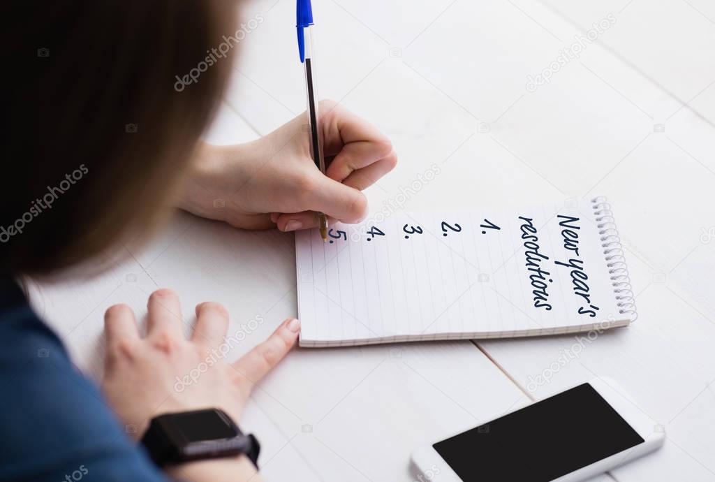 woman writing New year's resolutions list on table