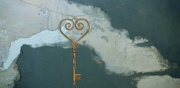 Gold heart key against rusty weathered wall