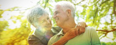 Güneşli bir günde bir parkta gülümseyen mutlu yaşlı çift