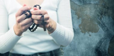 Midsection of woman holding rosary beads against rusty weathered wall clipart
