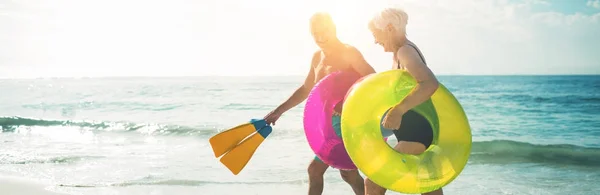 Gelukkige Senior Paar Wandelen Strand Met Opblaasbare Ringen Flippers Tijdens — Stockfoto
