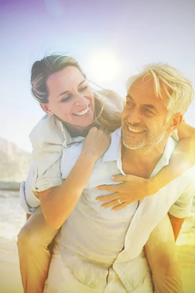 Man Δίνοντας Σύζυγό Του Χαμογελώντας Ένα Γουρουνάκι Πίσω Στην Παραλία — Φωτογραφία Αρχείου