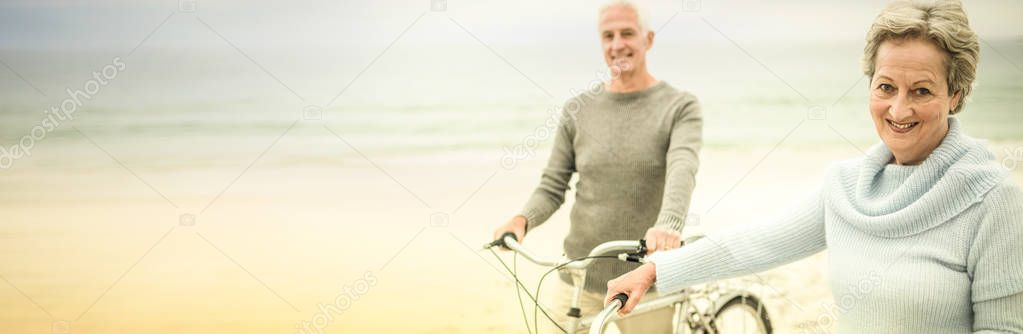 Portrait of happy senior couple with their bike on the beach