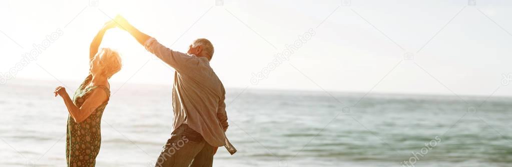 Senior couple dancing at beach on sunny day
