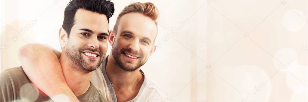 Smiling gay couple hugging at home