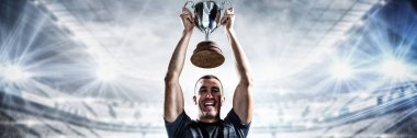 Stadyum gökyüzü karşı karşı kupayı tutarak başarılı rugby oyuncusu portresi