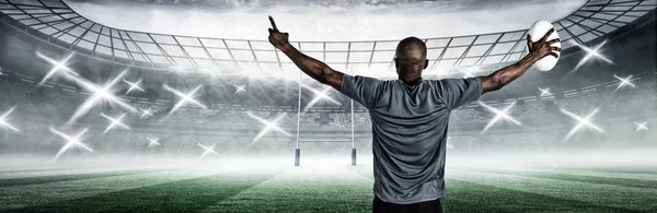 后视图的双臂的运动员提出举行橄榄球橄榄球体育场球 — 图库照片