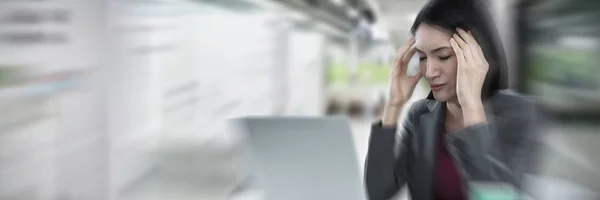有膝上型电脑的女实业家在现代办公室的走廊数字图像中遭受头痛的困扰 — 图库照片