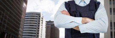 Mid section of security officer standing with arms crossed against view of modern office building clipart