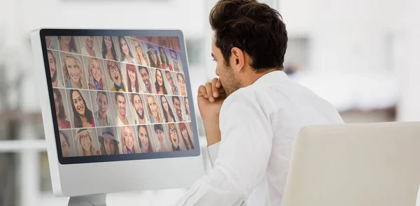 肖像画のコラージュに対してコンピューターのモニターを見ての実業家の背面図 — ストック写真