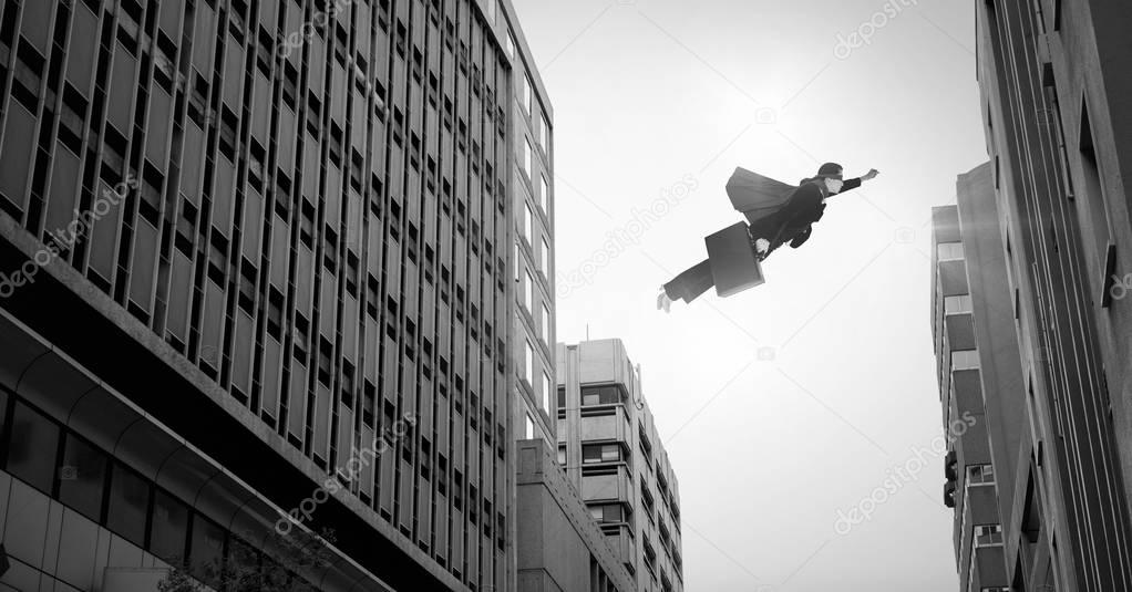 Digital composite of Businesswoman flying over surreal city buildings perspective