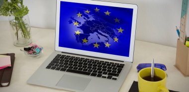 Laptop ve Avrupa Birliği bayrağı karşı masada çeşitli ofis aksesuarları