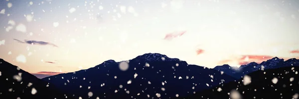Sneeuw Vallen Tegen Ondergaande Zon Achter Rotsachtige Gebergte — Stockfoto
