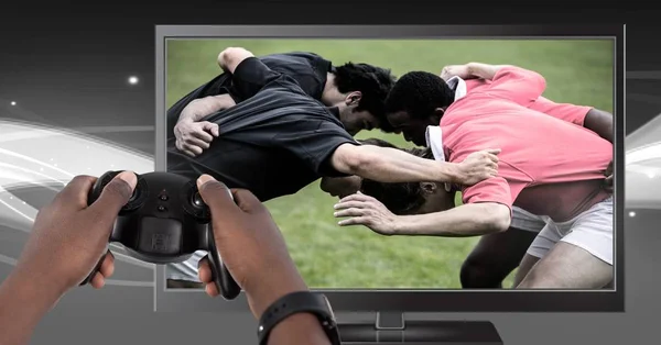 Composto Digital Mãos Segurando Controlador Jogos Com Jogadores Rugby Televisão — Fotografia de Stock