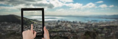 Şehir ve bulutlu gökyüzü manzara karşı beyaz arka plan dijital tablet dokunmadan eller