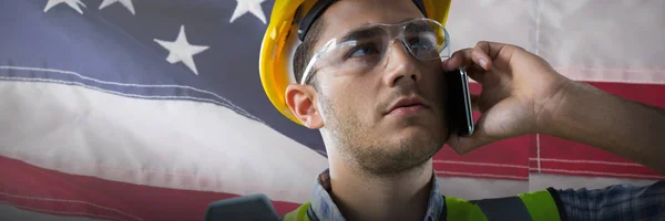 Serious construction worker on the phone against close-up of red and white american flag