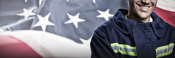 アメリカの国旗のクローズ アップに対して笑みを浮かべて消防士 — ストック写真