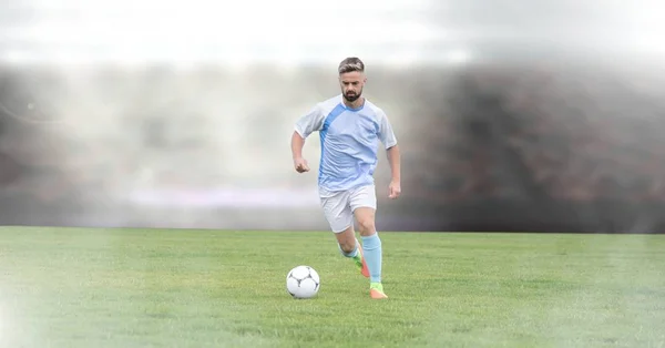 Digital composite of Soccer player on grass with stadium
