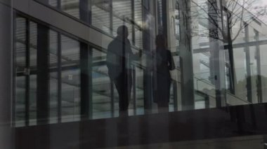 Erkek ve kadın profesyonellerin ön planda ağaç ve binalarla dolu modern ofisin girişinde buluşmalarının animasyonu
