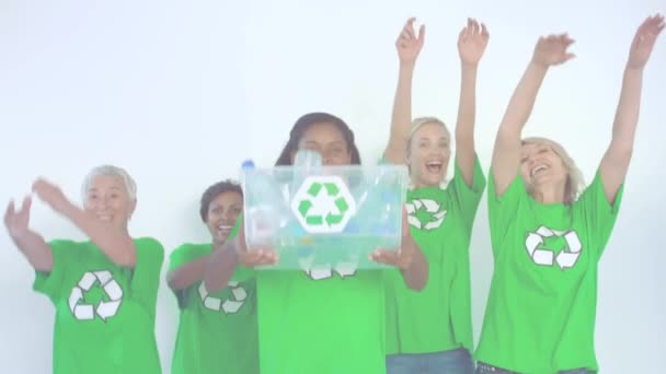 プラスチック製の箱からペットボトルを投げ 空気中の腕で応援するリサイクル標識のある緑のTシャツを着た多様な友人のグループのアニメーション — ストック動画