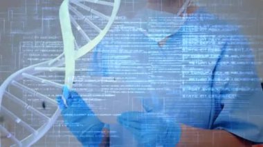 Ameliyathanede tablet bilgisayar kullanan beyaz kadın cerrah üzerinde DNA iplikçiklerinin dönmesi ve veri işleme animasyonu.