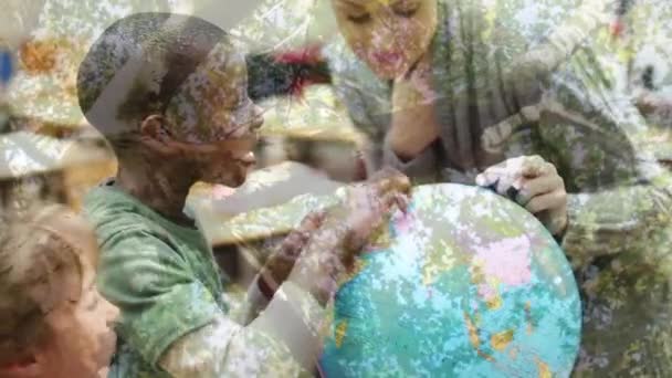 白人女教师和混血儿在学校利用地球仪与树木进行动画创作的前景 — 图库视频影像