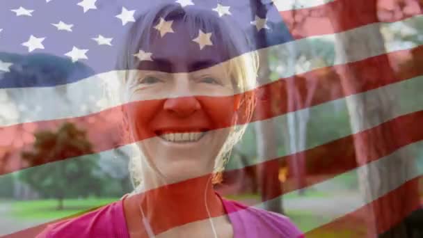 前景にアメリカ国旗を振りながらカメラに微笑む白人女性のアニメーション — ストック動画
