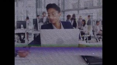 Bantlı ve parazitli bir ekranın animasyonu, akıllı giyimli melez bir kadının masa başında oturup kahve içmesini ve yoğun bir ofiste dizüstü bilgisayar kullanmasını gösteriyor.