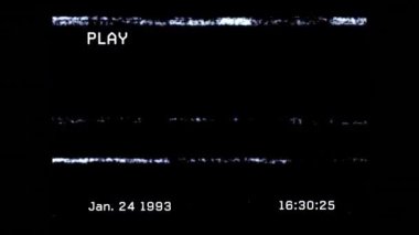 Oyun sözcüğü, beyaz metindeki tarih ve saat ve hızlı hareket eden parazit bantlarıyla siyah ekranın animasyonu