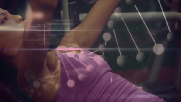 Animation d'un brin d'ADN 3D tournant et analyse informatique, avec une femme métissée allongée et s'entraînant avec des haltères en arrière-plan au ralenti 