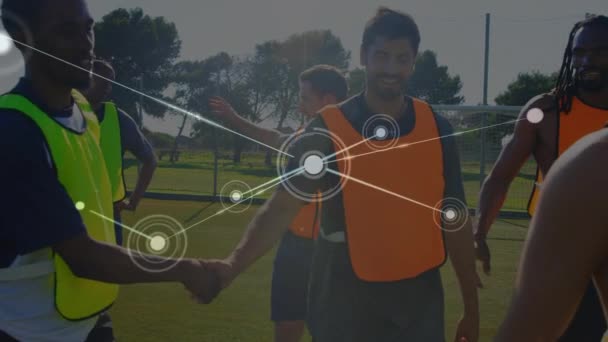 背景にあるサッカーの試合でピッチ上で握手をするサッカー選手のチームとの接続とデータ共有のネットワークのアニメーション — ストック動画