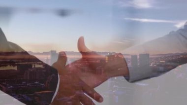 Şehir manzarası konusunda hemfikir olan iş adamlarının el sıkışması ve arka planda mavi gökyüzü bulutları.. 