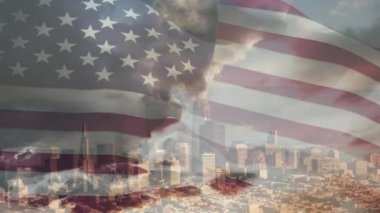 Güneşli bir günde, arka planda mavi gökyüzünde bulutlar olan modern bir şehir manzarasının önünde Amerikan bayrağı sallamanın animasyonu. 