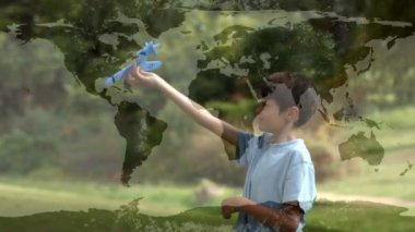 Dünya haritasıyla küresel bağlantılar ve veri işleme ağının animasyonu ve arka planda model bir uçakla oynayan bir çocuk. 