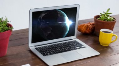 Not defteri, bitki ve bir fincan kahveyle birlikte masadaki dizüstü bilgisayarın ekranında dönen dünyanın animasyonu. Bu görüntünün elementleri NASA tarafından desteklenmektedir