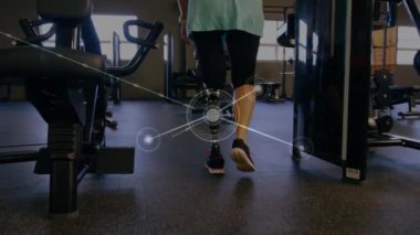 Veri işleme ve istatistik kaydının animasyonu, arka planda bir spor salonunda yürüyen protez bacaklı beyaz engelli bir bayan sporcuyla. 