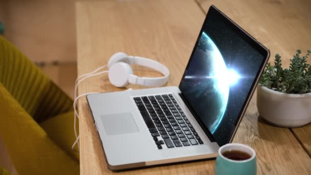 ヘッドフォン コーヒーカップを机の上にラップトップコンピュータの画面に表示される地球回転のアニメーション この画像の構成要素はNasa社製 — ストック動画