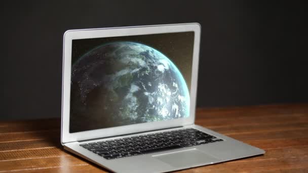 デスクとグレーの背景にラップトップコンピュータの画面に表示される地球回転のアニメーション この画像の構成要素はNasa社製 — ストック動画