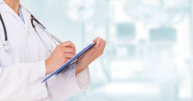 Kadın doktorun laboratuvar önlüğü ve steteskop giydiği orta bölüm. Elinde bir pano, hastanede çalışırken notlar tutuyor.. 