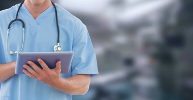 Hastanede çalışan, ameliyat önlüğü ve steteskop takmış, dijital tablet kullanan bir erkek doktorun orta bölümü.. 