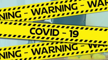Coronavirus Covid-19 virüsü yayılan yaşlı bir adamın tekerlekli sandalyesinde oturması üzerine sarı ve siyah bant üzerine siyah harflerle yazılmış Uyarı Covid-19 kelimelerinin animasyonu..