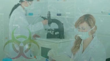 Veri işleme, sağlık tehlikesi işareti ve Coronavirus Covid-19 'un mikroskopla çalışan ve laboratuarda koruyucu yüz maskeleri ve cerrahi eldivenlerle test eden kadın bilim adamları üzerinde yayılması..